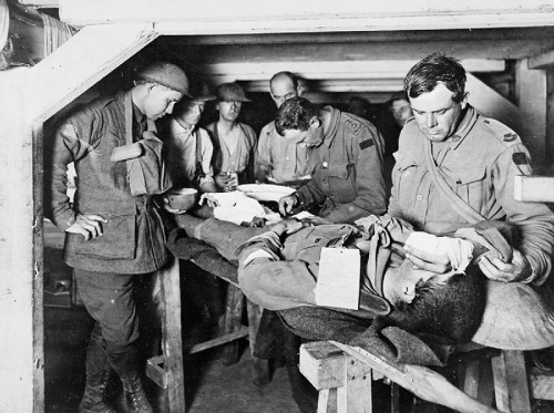 An Australian Medical Officer attends a wounded man at an Advanced Dressing Station during the Third Battle of Ypres in 1917. Imperial War Museum copyright image E(AUS)714.